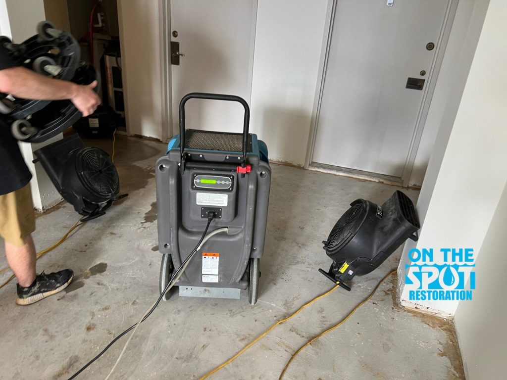 A restoration area with a water extraction machine and fans placed on a concrete floor, likely drying out after water damage.