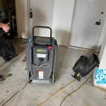 A restoration area with a water extraction machine and fans placed on a concrete floor, likely drying out after water damage.