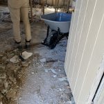 An under-construction area with a person standing near a wheelbarrow, surrounded by debris on the floor.